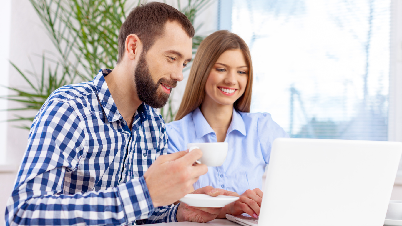 Male and female smiling at computer screen